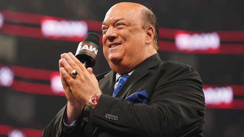 Paul Heyman holding a WWE Raw microphone and grinning