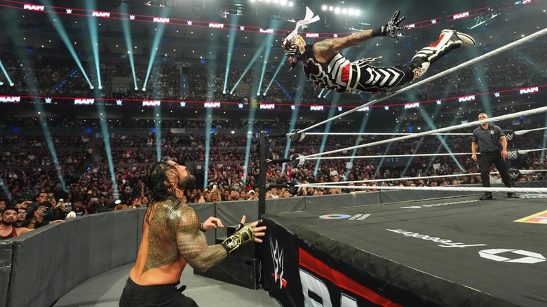 Penta diving over the top rope on Roman Reigns