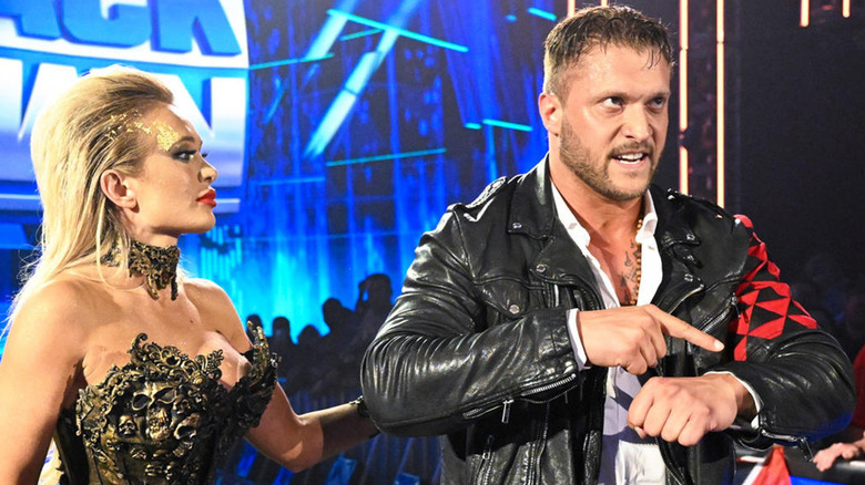 Scarlett holding Karrion Kross' arm