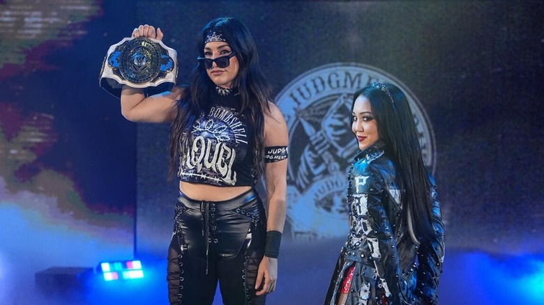 WWE Women's Intercontinental Champion Raquel Rodriguez holds up her title and poses alongside Roxanne Perez on the stage before a match on an August 2026 edition of 