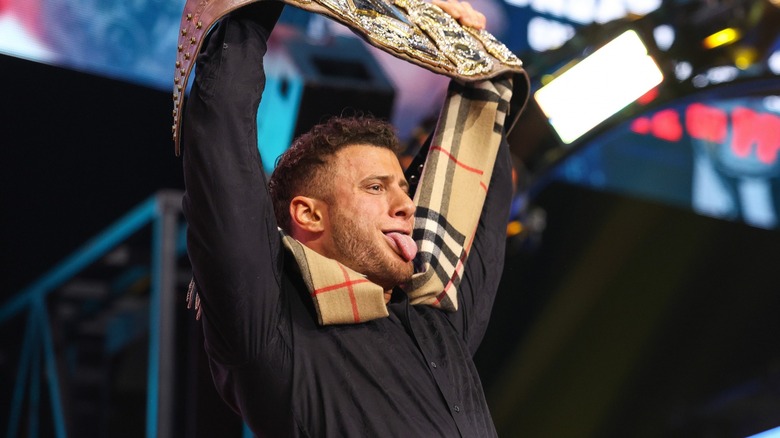 MJF holds his title overhead while goofily sticking his tongue out