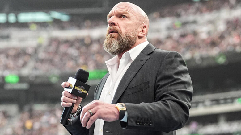 Triple H holds a microphone at WrestleMania as he prepares to speak to the crowd.