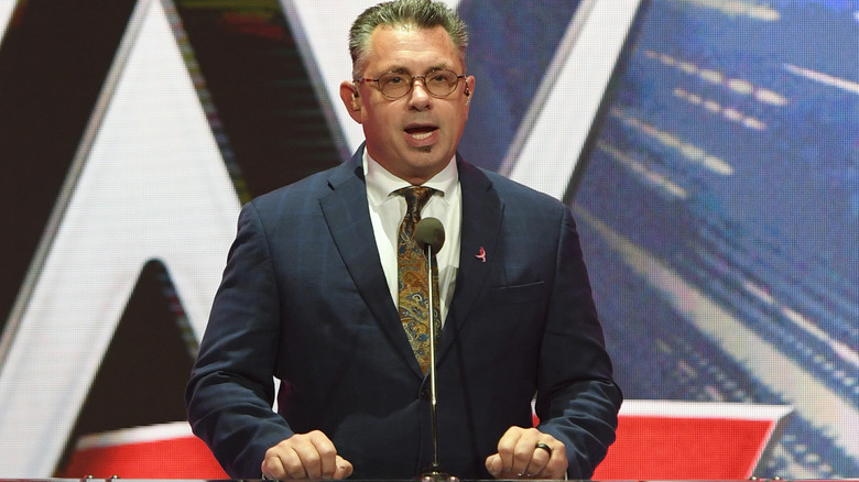 WWE's Michael Cole makes an announcement at the podium during a WWE press conference.