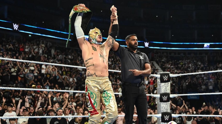 Rey Fenix holds the AAA Cruiserweight Championship high as a referee raises his arm following a victory on 
