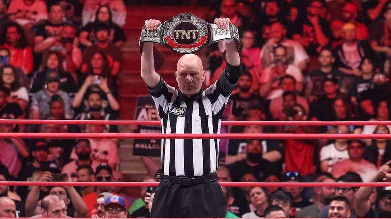 Rick Knox holding up the AEW TNT Championship looking off to the side