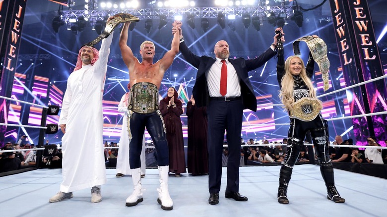 WWE CCO holds the arms of the 2024 Men's and Women's Crown Jewel Champions Cody Rhodes and Liv Morgan, respectively in 2024