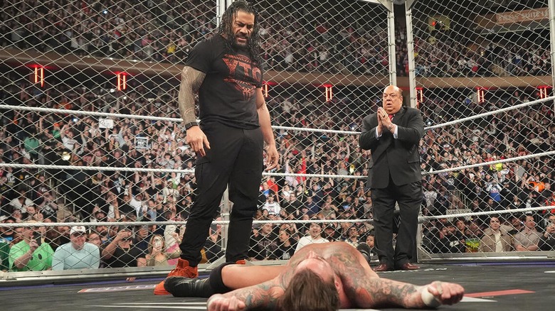 Roman Reigns looking over CM Punk after laying him out during his Cage Match on 