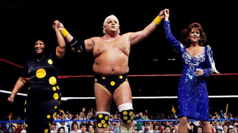 Sweet Sapphire, Dusty Rhodes y la Sra. Elizabeth, de pie en el ring con los brazos levantados.