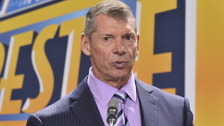 Vince McMahon standing in front of a microphone