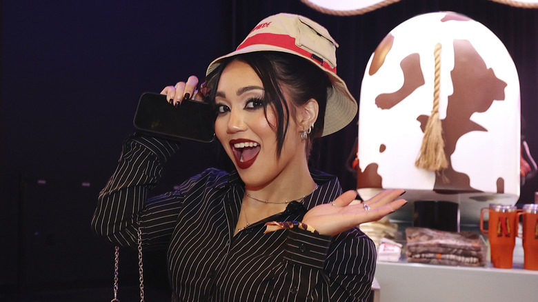 Roxanne Perez holds her phone while wearing a hat