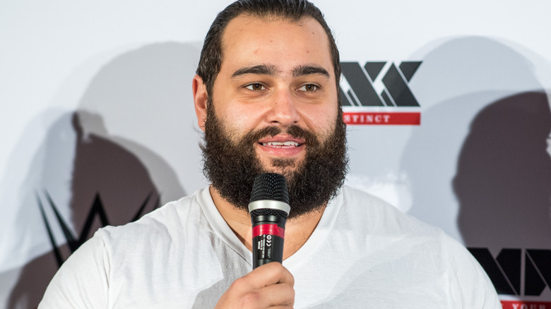 Rusev is holding a microphone
