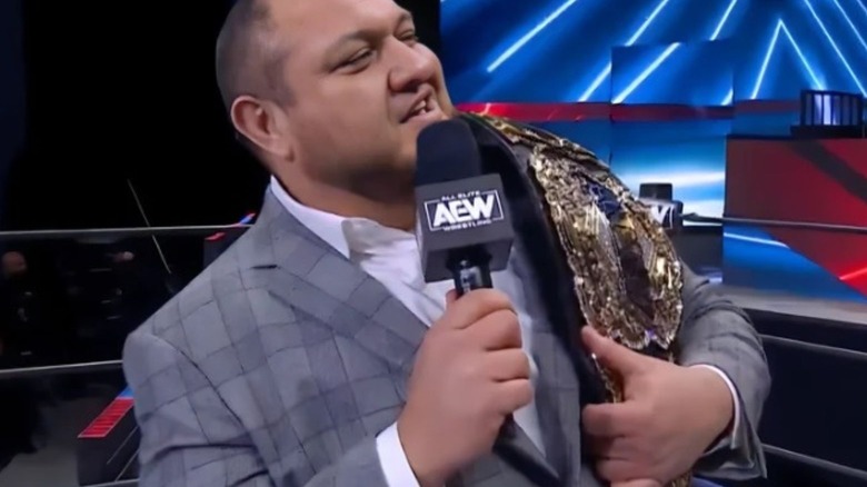 Samoa Joe delivers a promo in the AEW ring while holding his newly designed AEW World Championship.