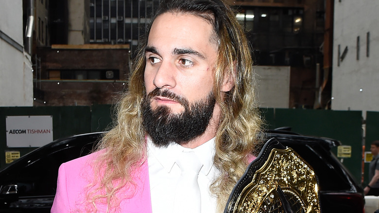 Seth Rollins holding the WWE World Heavyweight Championship in a pink suit