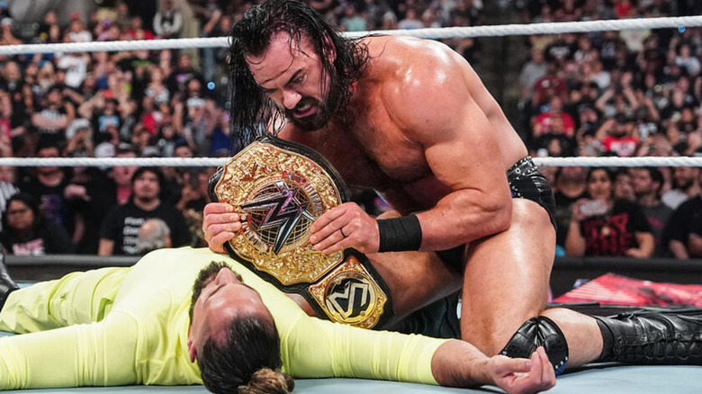 Drew McIntyre holding up Seth Rollins' title
