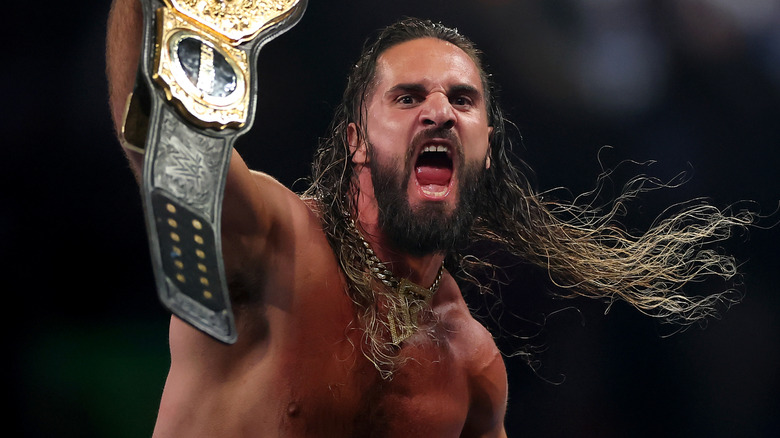 Seth Rollins shouts as he hoists up the WWE World Heavyweight Championship.