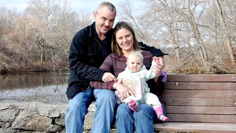 Spike Dudley posing for a picture with his wife and daughter in a park.