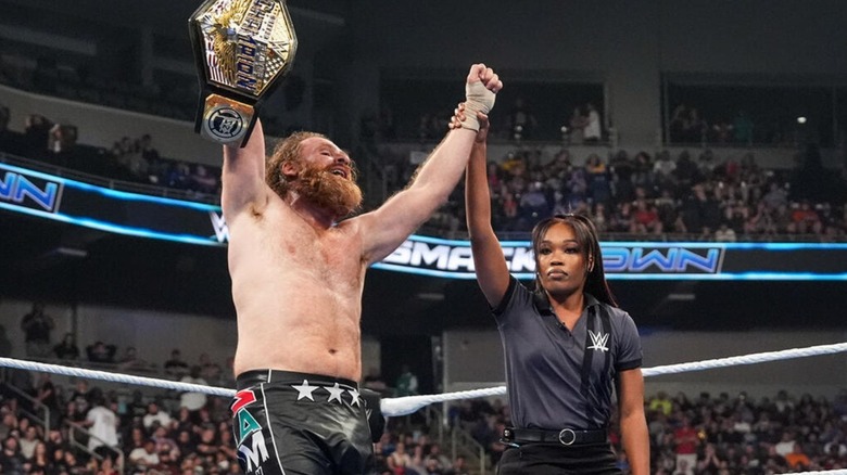A referee holds up Sami Zayn's hand in victory after a successful title defense on 