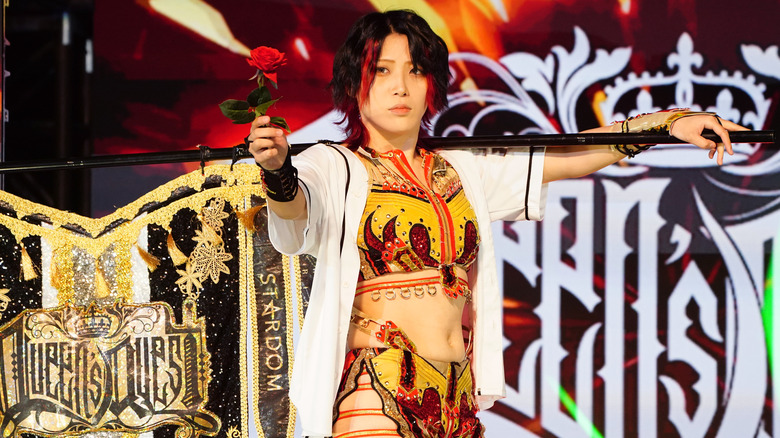 Utami Hayashshita posing with the Queen's Quest flag while holding a rose during her entrance