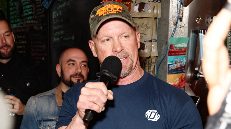Stone Cold Steve Austin talking into a mic with a Broken Skull Ranch hat on