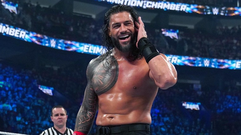 Roman Reigns checking his jaw and ear
