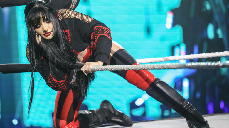 Tatum Paxley touches her face as she leans out from in between the middle and bottom rope.
