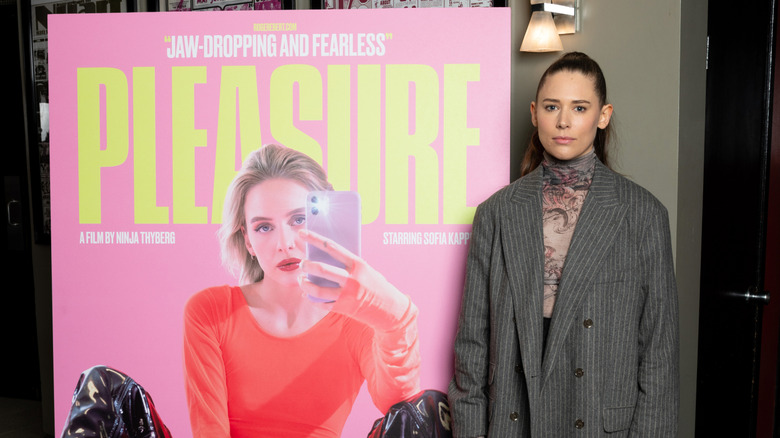 Ninja Thyberg stands next to the poster for her film Pleasure