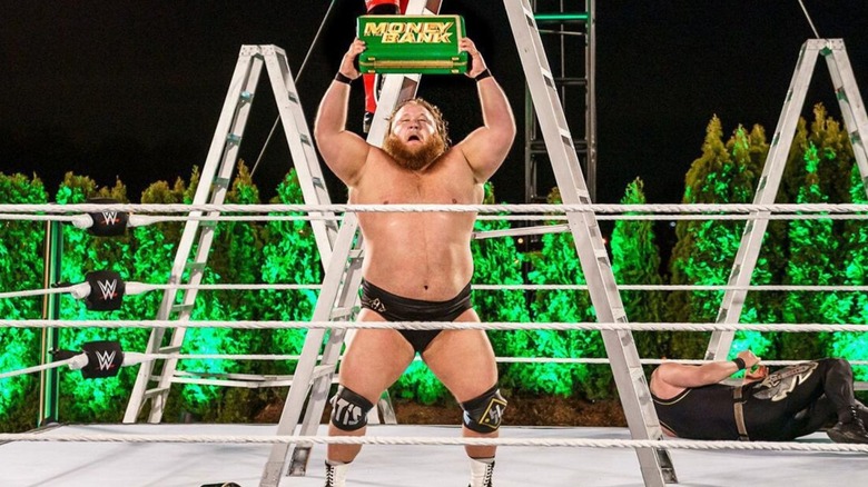 Otis raises the Money in the Bank briefcase over his head, after he technically won the match by grabbing the case after it fell from the top of the ladder.