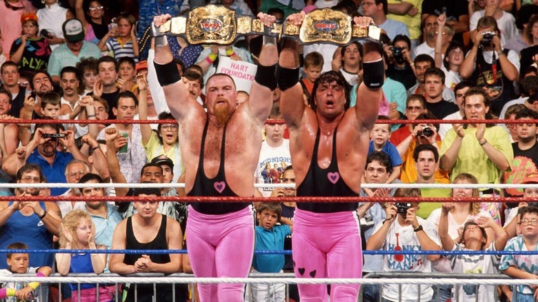 The Hart Foundation show off their championships.