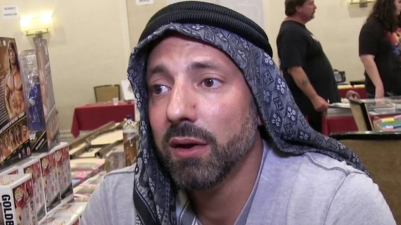The former Muhammad Hassan sits in front of a table at a convention during an interivew.