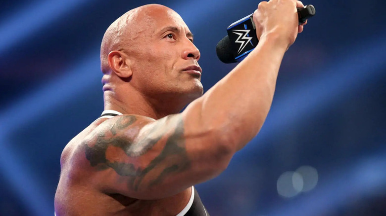 The Rock stands valiantly with a microphone in his hand.