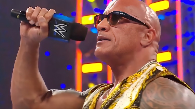 The Rock raises a microphone to his lips