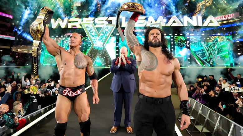 The Rock and Roman Reigns hold up title belts