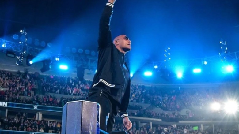 The Rock makes his return on an episode of "WWE SmackDown" and poses for the crowd on the turnbuckle.