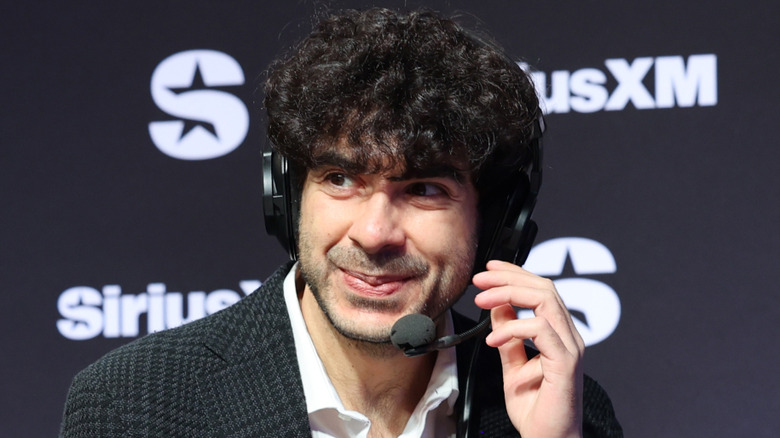 Tony Khan smiling and touching his headset