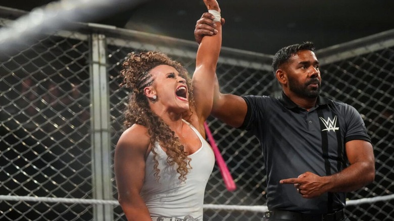 A referee holds up Jordynne Grace's hand after she defeated Blake Monroe in their weaponized steel cage match at No Mercy.