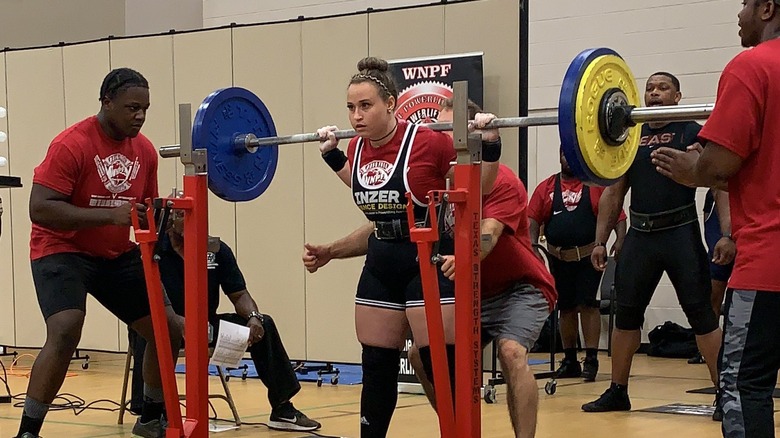 Jordynne Grace gets the bar behind her shoulders for a squat during a powerlifting competition in a photo posted by Rachael Ellering on X.