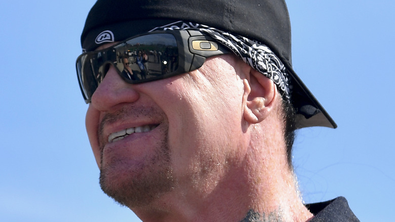 The Undertaker with sunglasses and a hat on smiling