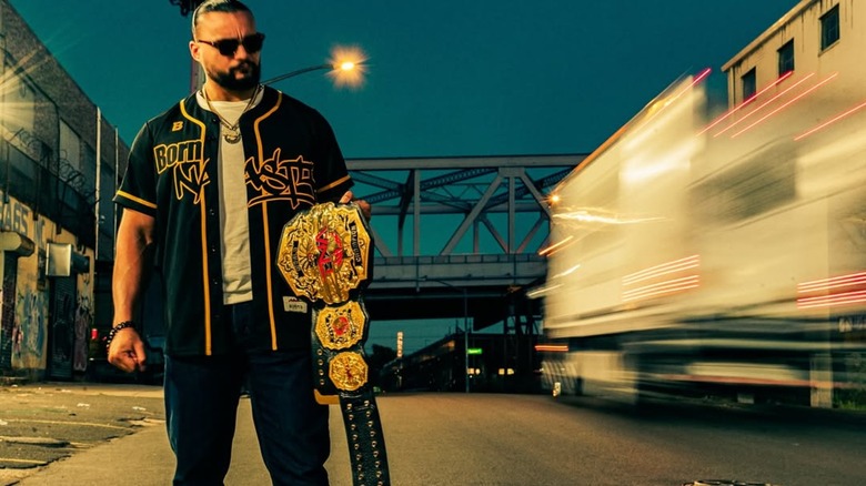 Mike Santana posing with the TNA World Championship for a photoshoot in public.