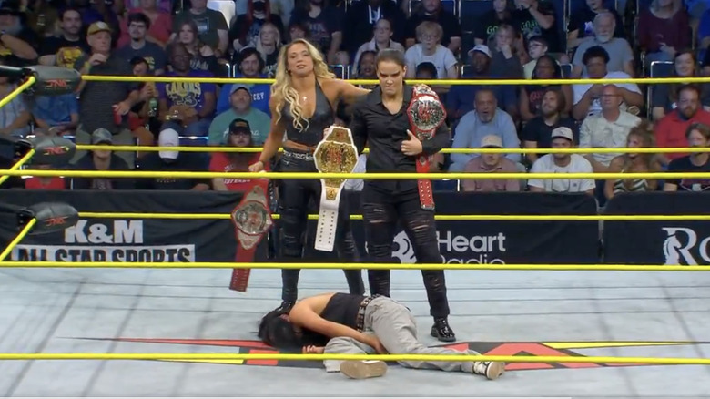 Shayna Baszler and Zoey Serrano standing over Indi Hartwell