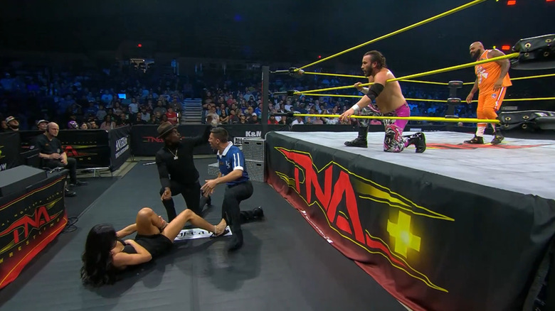 Mila Moore and Expressions outside the ring as John Skyler and AJ Francis wrestle in the ring