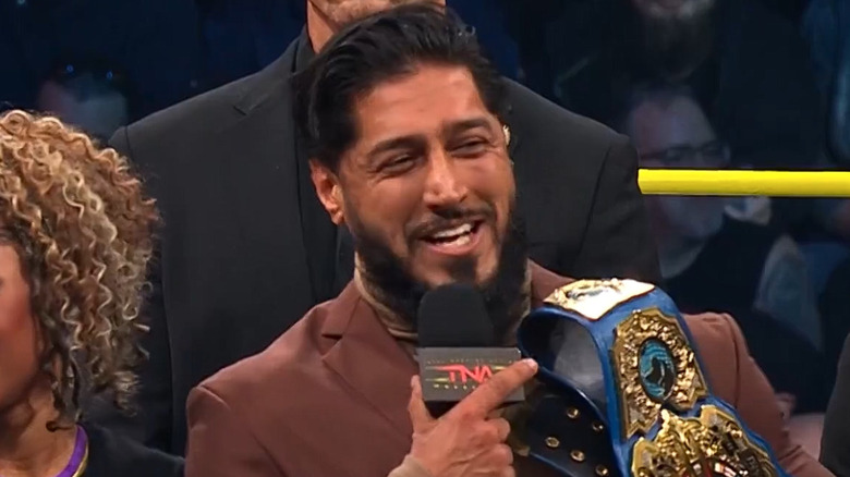 Mustafa Ali holding a microphone