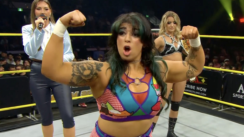 Forza flexing her biceps as Brookside watches her from behind