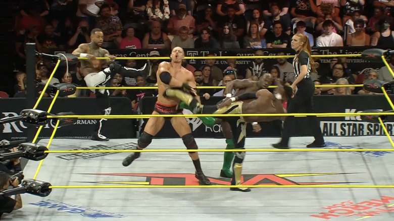 BDE and Swann delivering a double superkick to Agent 0 as Miguel watches from the ring apron