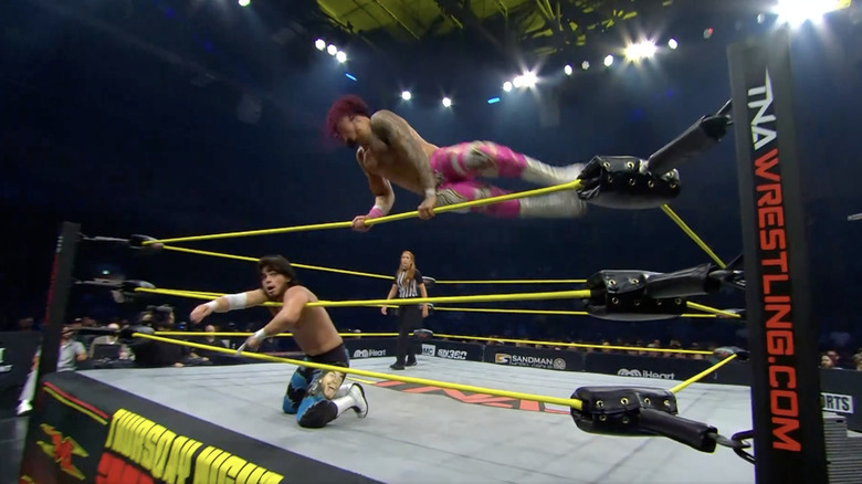 Navarro flying over the top rope to deliver a kick on Alonzo through the ropes