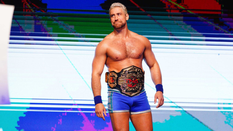 Joe Hendry poses on stage, wearing the TNA World Championship around his waist, before at match at Under Siege.