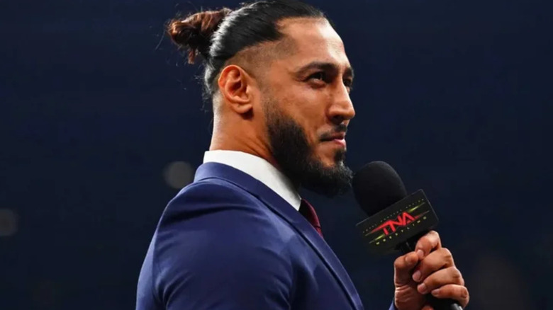 Mustafa Ali is holding a microphone