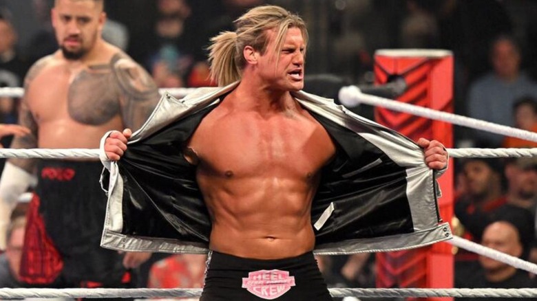 Dolph Ziggler shows off his abs on the apron of the ring as Solo Sikoa waits behind him before a match on 