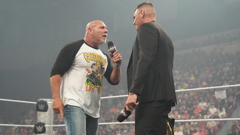 Goldberg and Gunther in the ring holding microphones