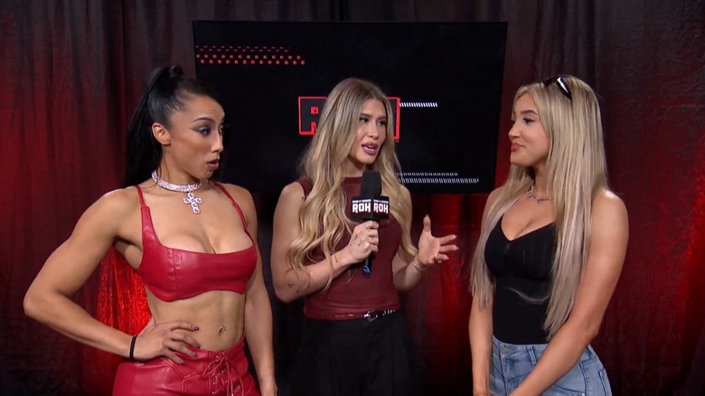 Zayda Steel speaks with Leila Grey backstage, interviewer Alicia Atout between them with a microphone in hand, during an episode of Ring of Honor.