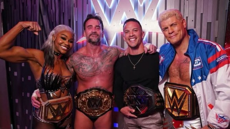 Jade Cargill, CM Punk, Ricky Saints, and Cody Rhodes pose backstage in gorilla position with their championships.